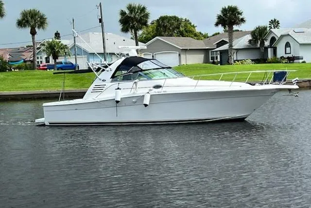 Slide: The Image of 2001 Sea Ray 340 Amberjack boat cruising on a calm waterway near residential homes. - 0