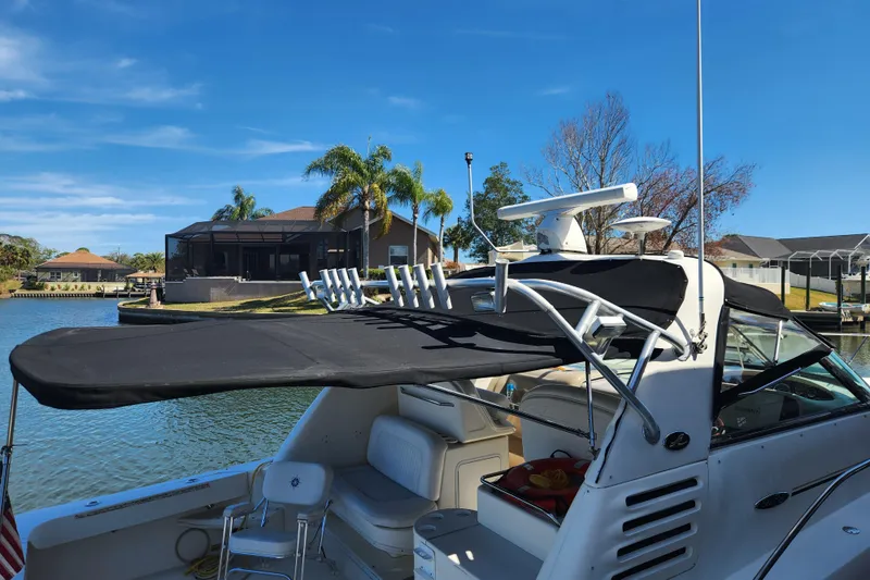 Slide: The Image of 2001 Sea Ray 340 Amberjack boat docked by waterfront homes, featuring a black canopy. - 4