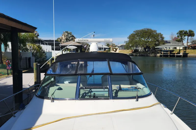 Slide: The Image of 2001 Sea Ray 340 Amberjack docked by a serene waterfront with clear blue skies. - 7