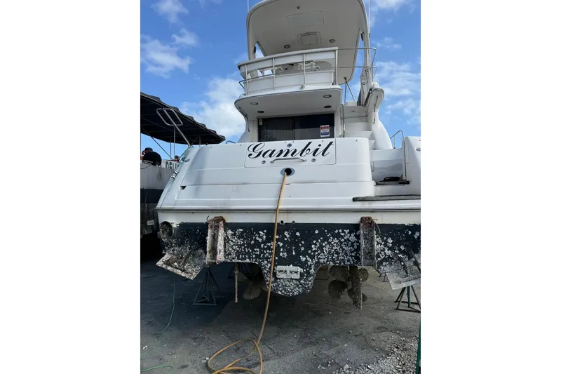 Slide: The Image of 2001 Sea Ray 560 Sedan Bridge yacht on land, showing rear view and name "Gambit." - 4