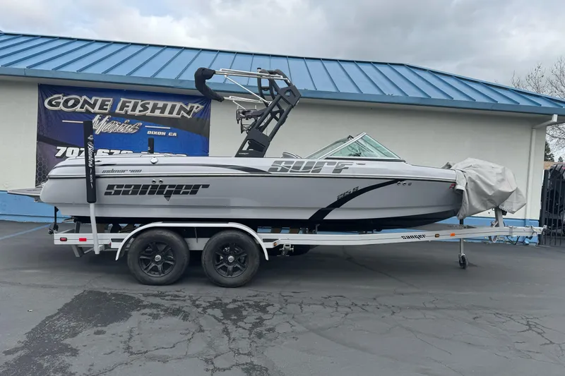 Slide: The Image of 2024 Sanger 215 S boat on trailer at dealership, under cloudy sky. - 0