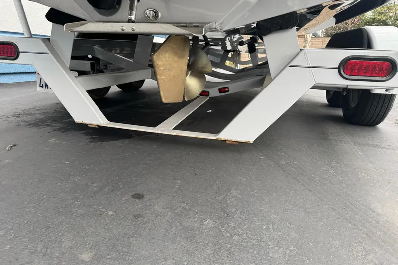Slide: The Image of Underneath view of a 2024 Sanger 215 S boat on a trailer, showing propeller and frame. - 23
