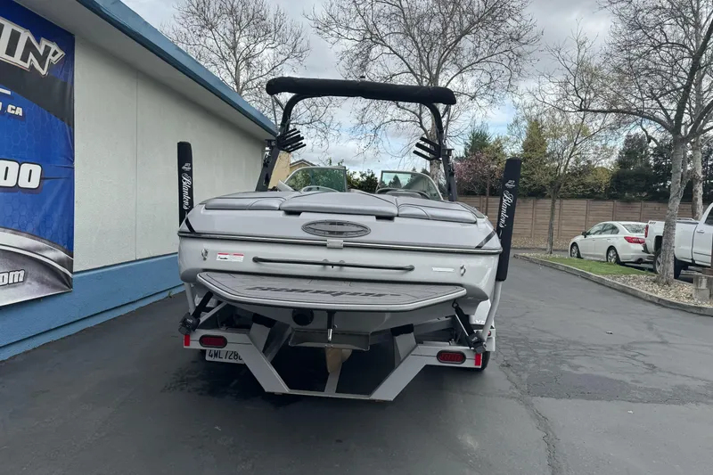 Slide: The Image of 2024 Sanger 215 S boat, rear view, parked outdoors near dealership. - 3