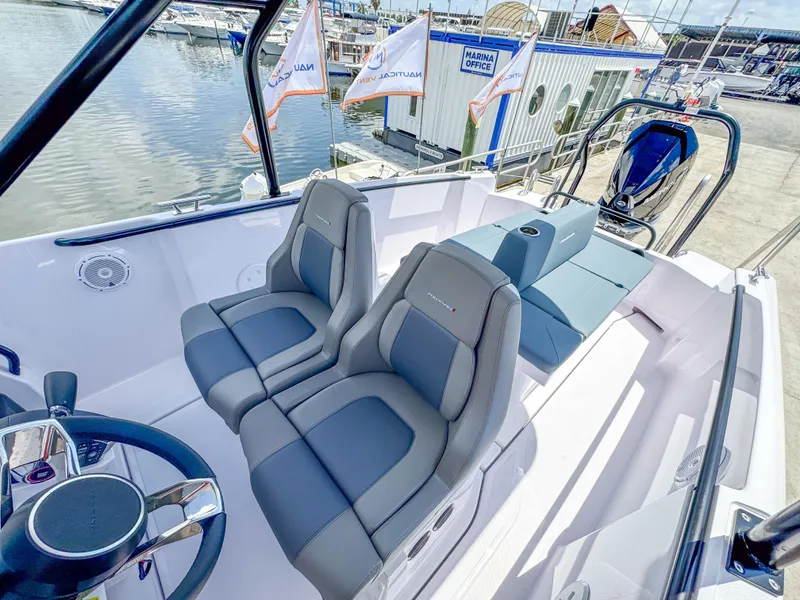 Slide: The Image of 2025 Axopar 25 Cross Top boat interior with sleek seating and modern design at a marina. - 5