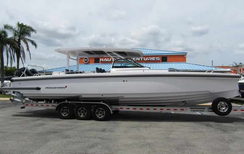 Slide: The Image of 2024 Axopar 37 Sun Top boat on a trailer, parked outdoors near palm trees. - 4