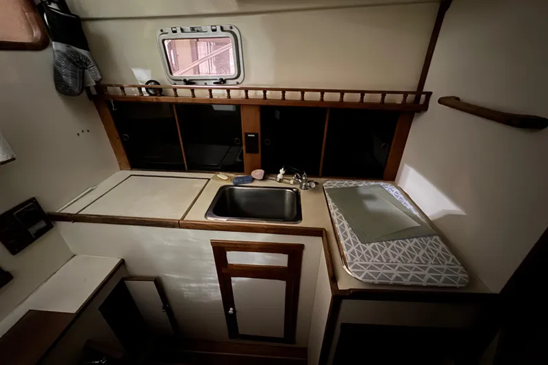 Slide: The Image of Compact kitchen area in a 1988 Blue Seas 31 boat, featuring a sink and storage. - 15