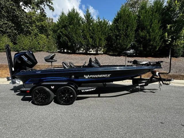 The Image of 2024 Phoenix Bass Boats 20 XE on trailer, parked outdoors with trees in background. - 0