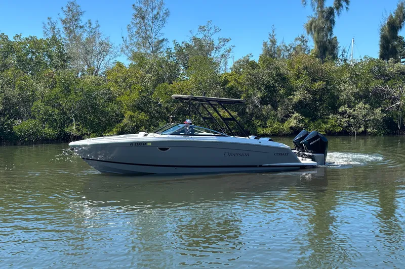 Slide: The Image of 2022 Cobalt R8 Outboard boat cruising on a calm river with lush greenery. - 4
