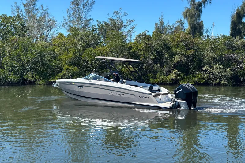 Slide: The Image of 2022 Cobalt R8 Outboard boat cruising on a calm river with lush greenery. - 5