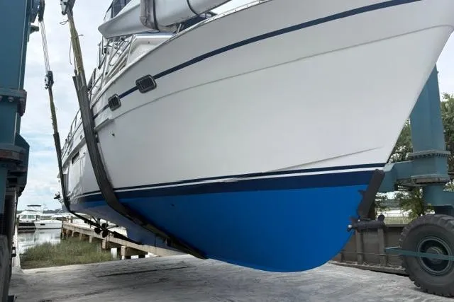 Slide: The Image of 1985 DeFever 40 Offshore Cruiser being lifted, showcasing its blue hull and sleek design. - 49
