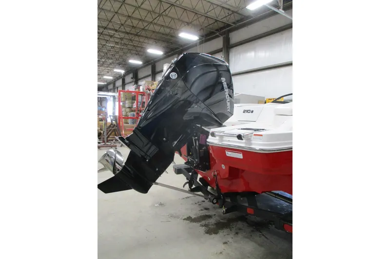Slide: The Image of 2025 Tahoe 210 S boat with Mercury outboard motor in a warehouse setting. - 1