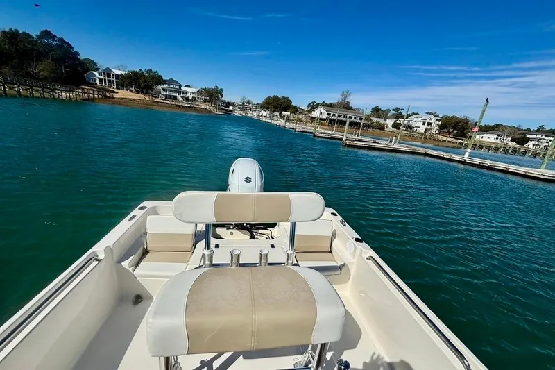 Slide: The Image of 2025 Bulls Bay 2200 XS boat cruising on a scenic waterway with docks and houses. - 11