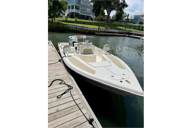 Slide: The Image of 2025 Bulls Bay 2200 XS boat docked on a calm waterfront. - 2