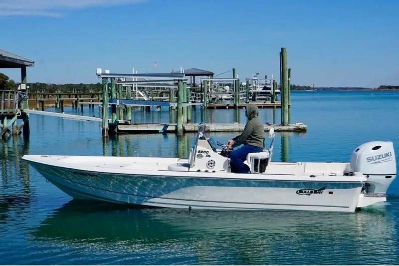 Slide: The Image of 2025 Bulls Bay 2200 XS boat cruising near a dock on a sunny day. - 6