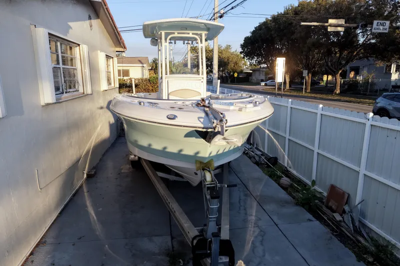 The Image of 2018 Robalo R242 Center Console boat on trailer beside house. - 0