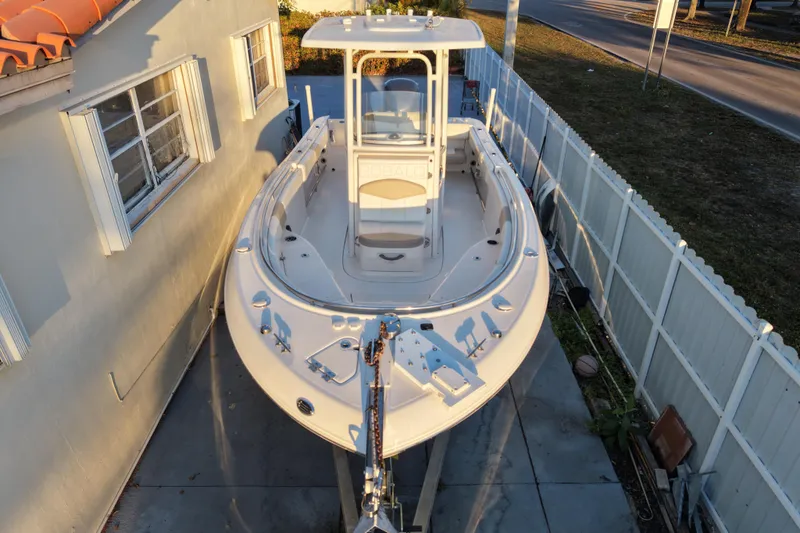 Slide: The Image of 2018 Robalo R242 Center Console boat parked beside a house and fence. - 14