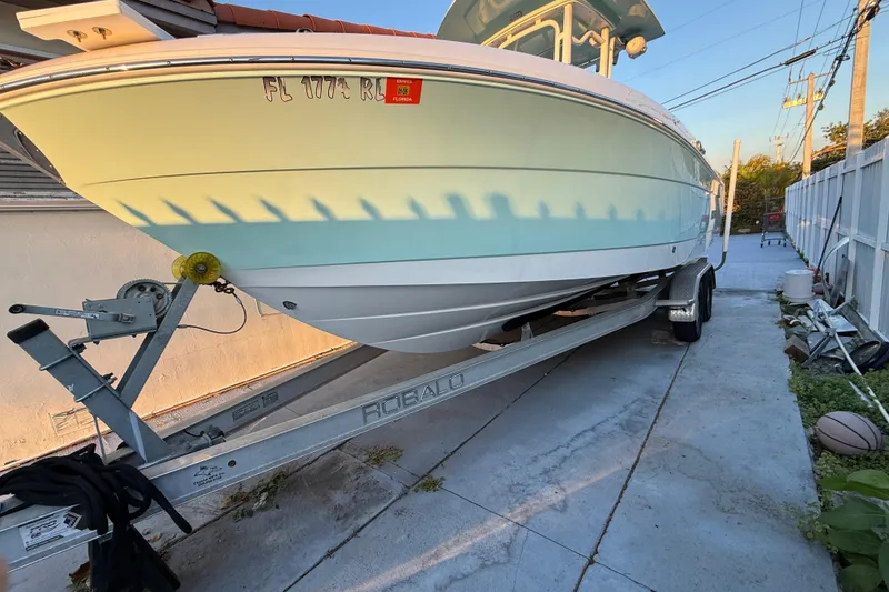 Slide: The Image of 2018 Robalo R242 Center Console boat on trailer in driveway. - 18