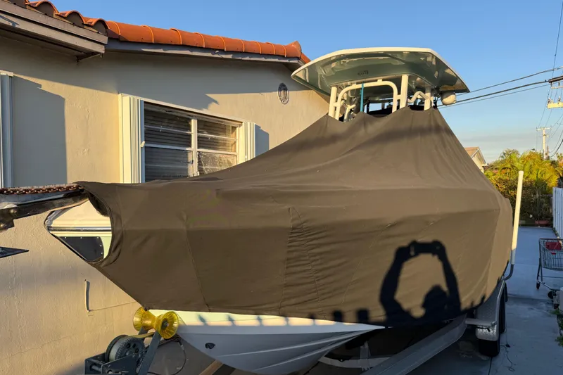 Slide: The Image of 2018 Robalo R242 Center Console boat covered, parked beside a house. - 19