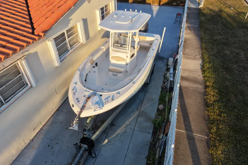 Slide: The Image of 2018 Robalo R242 Center Console boat parked beside a house. - 2