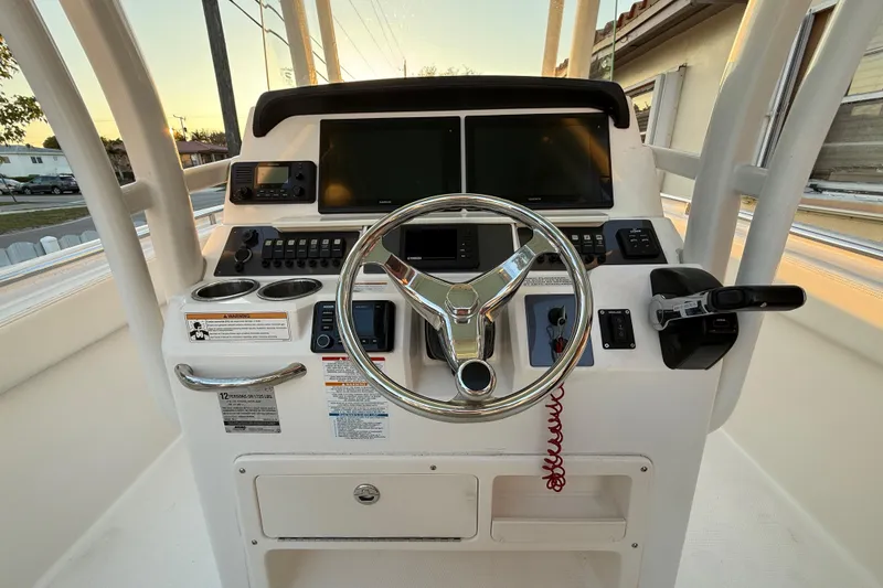 Slide: The Image of 2018 Robalo R242 Center Console boat dashboard with steering wheel and navigation screens. - 24