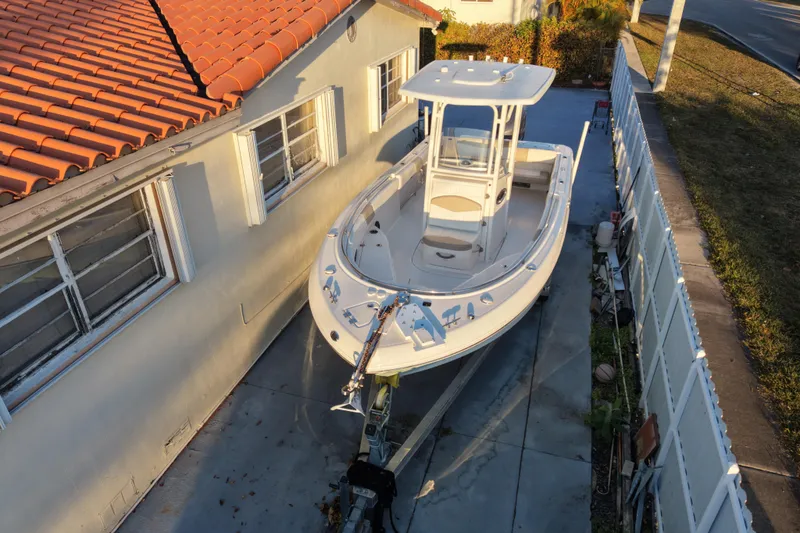 Slide: The Image of 2018 Robalo R242 Center Console boat parked beside a house with red roof tiles. - 3