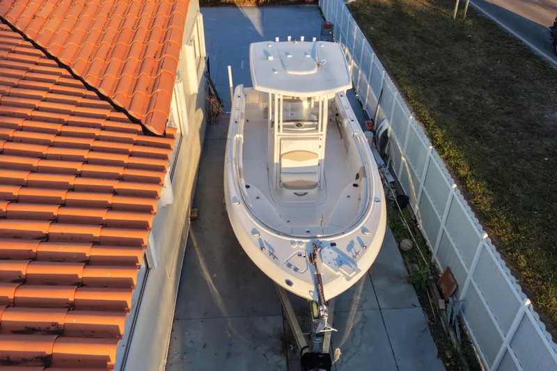 Slide: The Image of 2018 Robalo R242 Center Console boat parked beside a house with a tiled roof. - 5