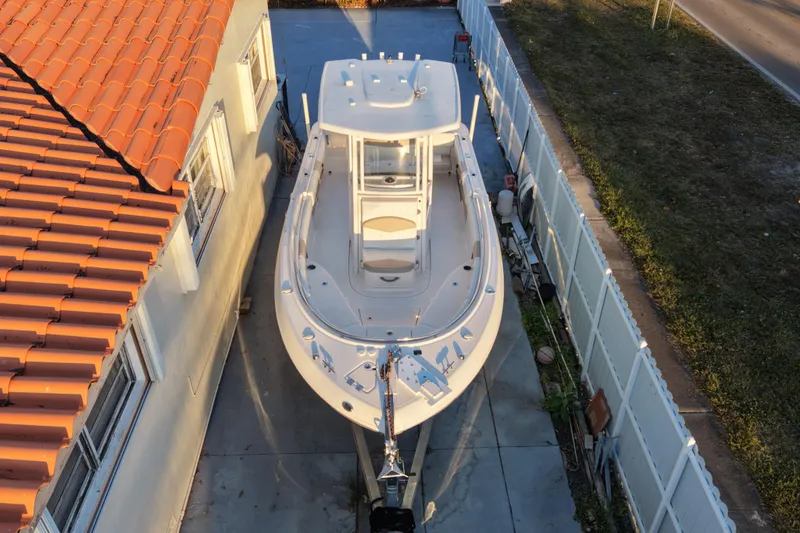 Slide: The Image of 2018 Robalo R242 Center Console boat parked beside a house with a tiled roof. - 6