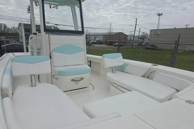 Slide: The Image of 2021 Robalo 246 Cayman boat interior with white and teal seating, docked outdoors. - 15