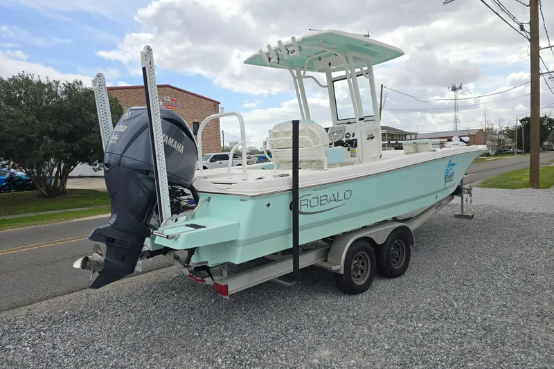 Slide: The Image of 2021 Robalo 246 Cayman boat on trailer with Yamaha engine, parked on gravel. - 2