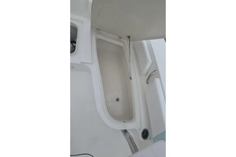 Slide: The Image of 2021 Robalo 246 Cayman boat storage compartment with open lid, showcasing interior space. - 22