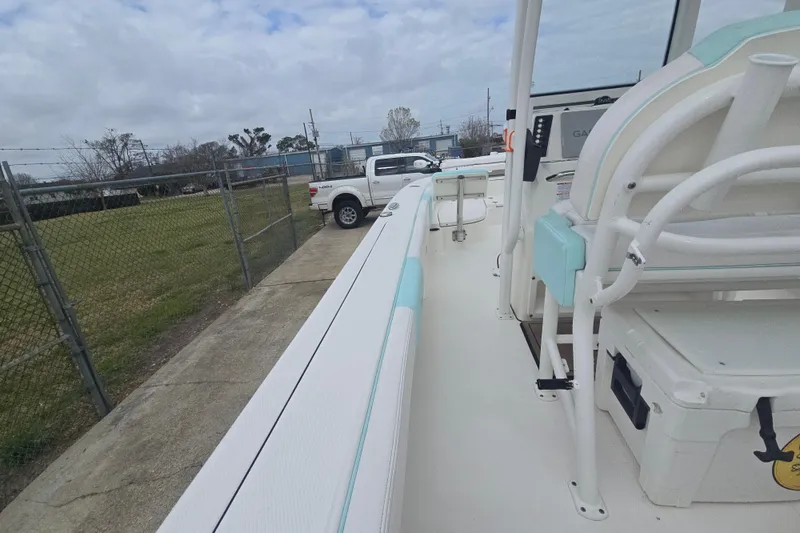 Slide: The Image of 2021 Robalo 246 Cayman boat interior with seating and storage, parked near a fence. - 26