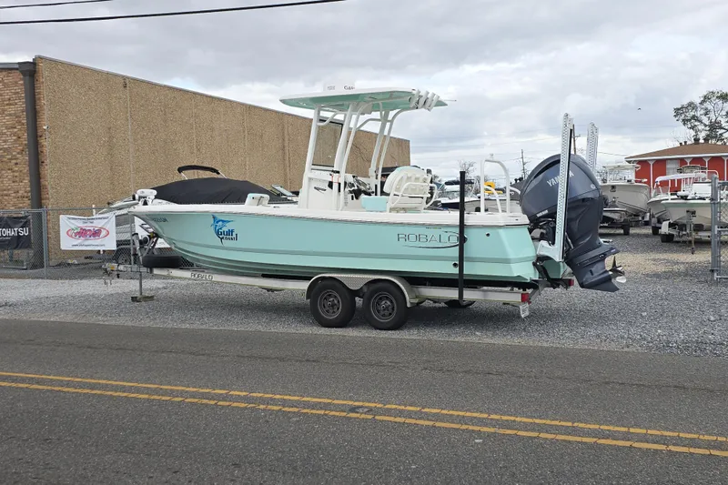 Slide: The Image of 2021 Robalo 246 Cayman boat on trailer, parked outdoors near a dealership. - 7
