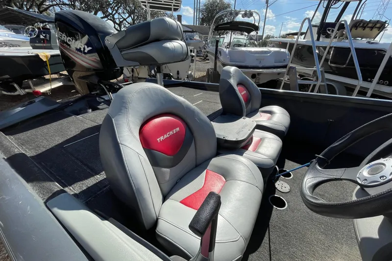 Slide: The Image of 2015 Tracker Pro Team 190 TX boat interior with red and gray seats, steering wheel, and Mercury engine. - 4