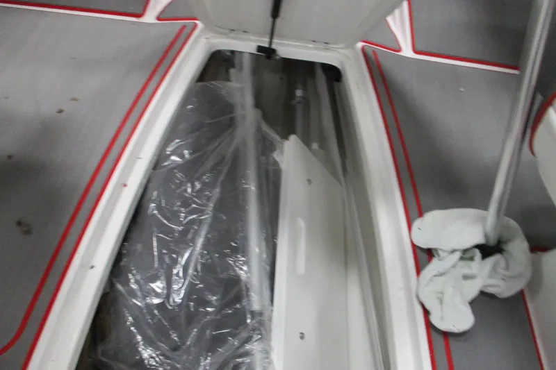 Slide: The Image of 2024 Tahoe 210 S Limited boat interior storage compartment with red trim accents. - 8