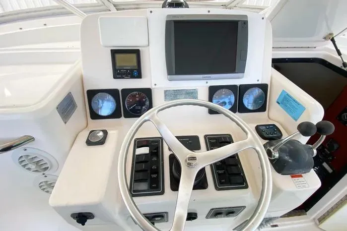Slide: The Image of Control panel of a 2001 Pursuit 3000 Offshore boat with steering wheel and gauges. - 13