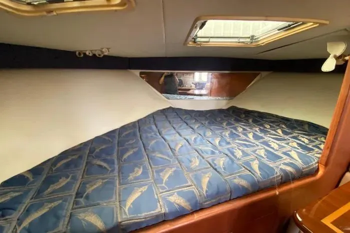 Slide: The Image of 2001 Pursuit 3000 Offshore cabin interior with blue patterned bedding and overhead window. - 28