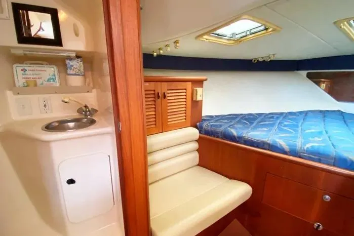 Slide: The Image of 2001 Pursuit 3000 Offshore cabin interior with bed, sink, and seating area. - 29