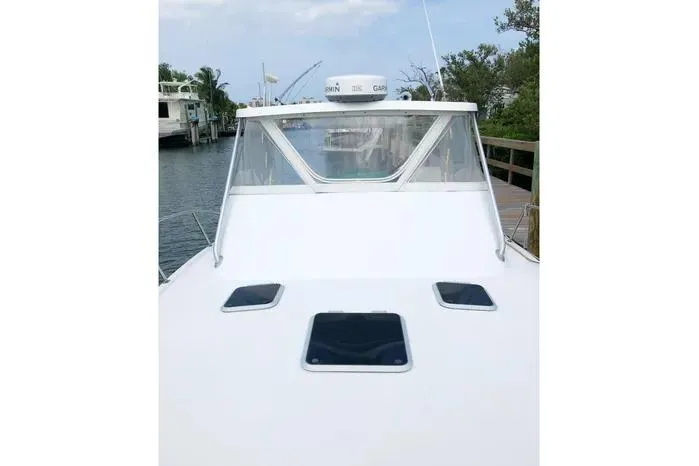 Slide: The Image of 2001 Pursuit 3000 Offshore boat docked, featuring a sleek white deck and windshield. - 3