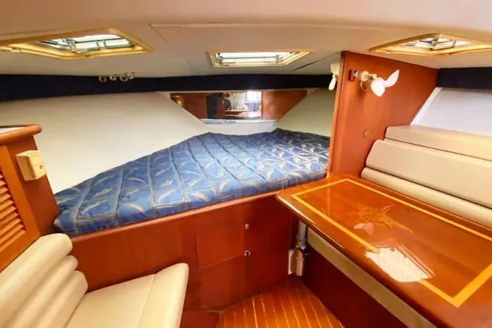 Slide: The Image of 2001 Pursuit 3000 Offshore cabin with bed, seating, and wooden table. - 31