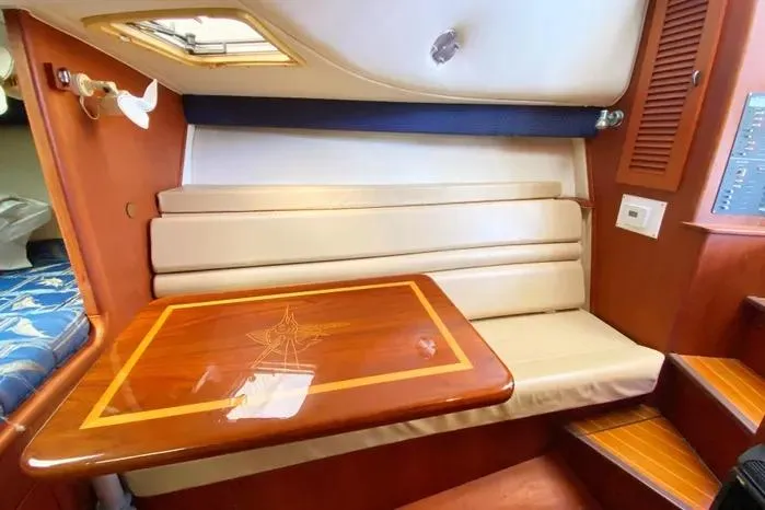 Slide: The Image of 2001 Pursuit 3000 Offshore cabin with wooden table and cushioned seating. - 36