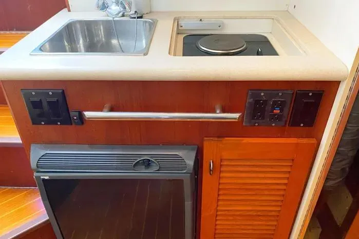 Slide: The Image of 2001 Pursuit 3000 Offshore boat kitchenette with sink, stove, and storage. - 37