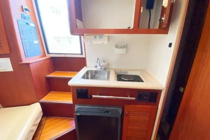 Slide: The Image of 2001 Pursuit 3000 Offshore boat kitchen with sink, stove, and wooden cabinetry. - 40