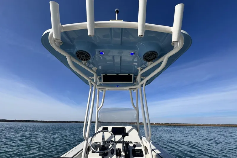 Slide: The Image of 2022 Carolina Skiff 24 Ultra Elite boat on water, featuring T-top and steering console. - 11