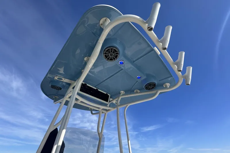 Slide: The Image of 2022 Carolina Skiff 24 Ultra Elite T-top with rod holders against blue sky. - 12