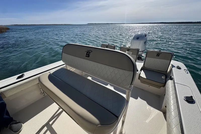 Slide: The Image of 2022 Carolina Skiff 24 Ultra Elite boat interior with seating and Suzuki outboard motor on water. - 16