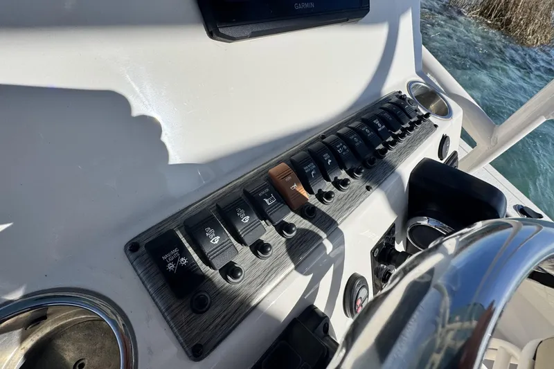 Slide: The Image of Control panel of 2022 Carolina Skiff 24 Ultra Elite boat with switches and steering wheel. - 2