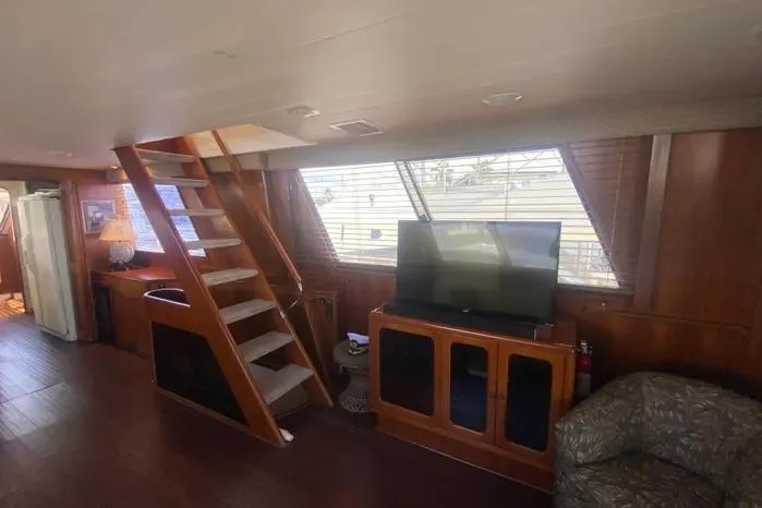 Slide: The Image of 1990 Viking Motor Yacht interior with wooden stairs, TV, and cozy seating area. - 10