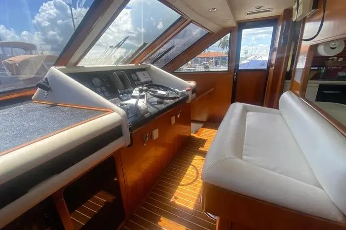 Slide: The Image of 1990 Viking Motor Yacht interior with helm, wooden flooring, and cushioned seating. - 27