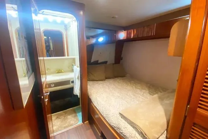Slide: The Image of Cozy bedroom and bathroom in a 1990 Viking Motor Yacht, featuring wood accents and soft lighting. - 32