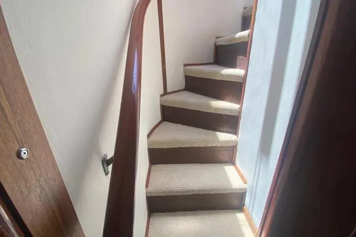 Slide: The Image of Staircase inside 1990 Viking Motor Yacht with wooden handrail and carpeted steps. - 35